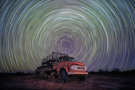 Image for Cleaning up the Cosmos article - Star trails from the Earth's rotation, captured using long exposure, above a cattle truck in the Western Australian Wheatbelt. Credit: Alamy